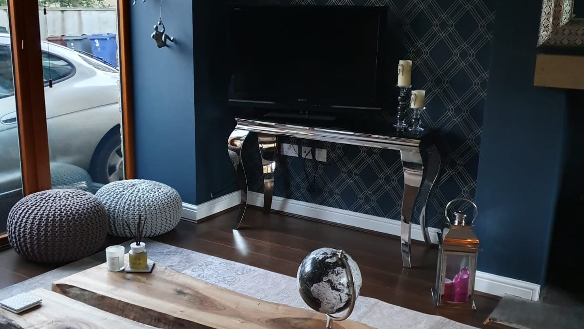 Modern Sheffield living space with deep navy geometric wall, mirrored console, TV and sofa. Painter and decorator project by Richard Walton.