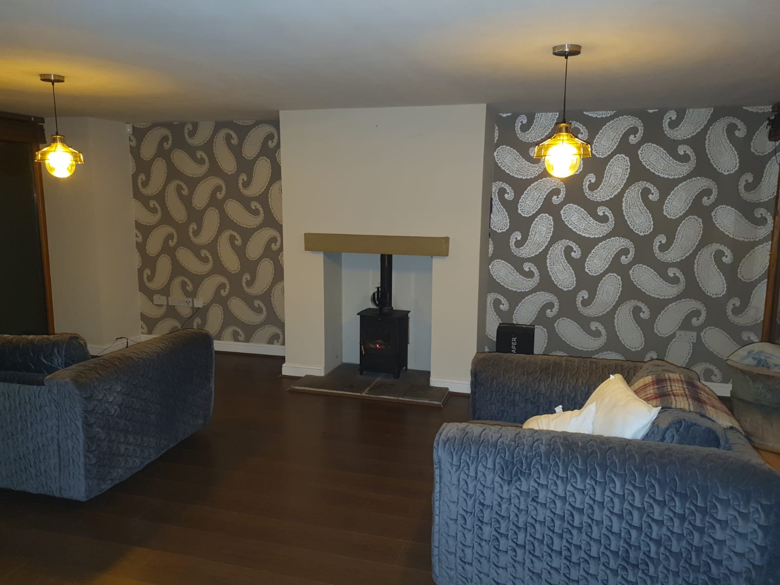 Sheffield lounge with grey paisley feature wall behind a log burner. Painted ceiling and architraves. Painter and decorator work by Richard Walton.
